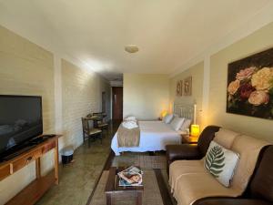 a hotel room with a bed and a couch at Pousada VillaSerrana in Monte Verde