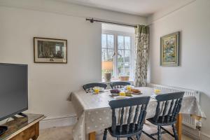 a dining room with a table with chairs and a television at South Cottage in Sherborne