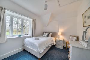 a white bedroom with a bed and a window at South Cottage in Sherborne