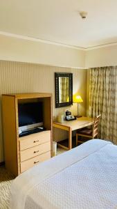 a hotel room with a bed and a desk with a television at Intercity Tower Hotels in San Pedro Sula