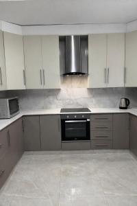 a kitchen with white cabinets and a stove top oven at Berna Coastal Retreat in Port Shepstone
