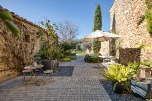 a patio with an umbrella and tables and chairs at Les Hamaques hotel in Viladamat