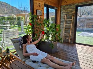 a woman is sitting on a couch on a porch at TRAPPEUR - Les Chalets du lac Belcaire in Belcaire