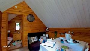 a log cabin with a table and a clock on the wall at TRAPPEUR - Les Chalets du lac Belcaire in Belcaire