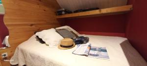 a bed with a hat and a book on it at TRAPPEUR - Les Chalets du lac Belcaire in Belcaire