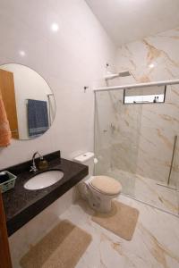 a bathroom with a sink and a toilet and a mirror at Casinha Aconchegante in Primavera do Leste