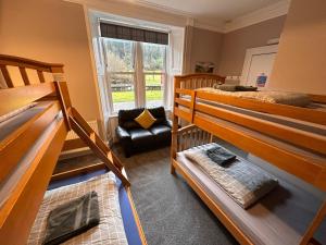 a room with three bunk beds and a chair at Great Glen Hostel in Spean Bridge