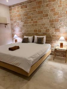 a bedroom with a large bed with a brick wall at Daumi House in Masbagik