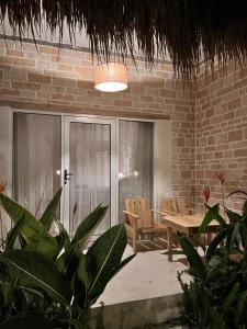 a patio with a table and chairs and a brick wall at Daumi House in Masbagik