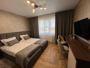a hotel room with two beds and a desk and a television at Amaro Hotel Uman in Uman