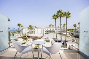 a balcony with a table and chairs and a view of the beach at Hipotels Barrosa Park in Chiclana de la Frontera