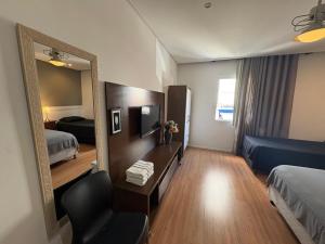 a hotel room with a mirror and a chair at Travessa 12 - Suítes centro de Serra Negra - SP in Serra Negra