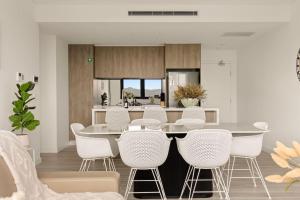 a kitchen with a table and white chairs at 2BDR Luxury Apartment Panoramic Views in Gosford