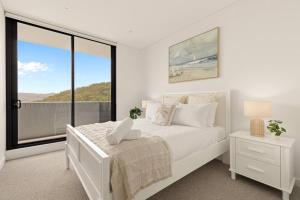 a white bedroom with a bed and a large window at 2BDR Luxury Apartment Panoramic Views in Gosford +17 photos