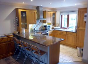 a kitchen with wooden cabinets and a island with bar stools at Cherry Tree Cottage in Glencoe