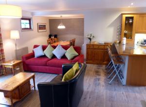 a living room with a red couch and a kitchen at Cherry Tree Cottage in Glencoe