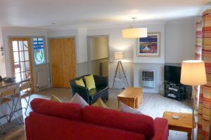 a living room with a red couch and a table at Cherry Tree Cottage in Glencoe