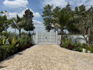 a driveway with a white gate in a garden at Phong Tom Retreat - Pet friendly location in Long Khanh