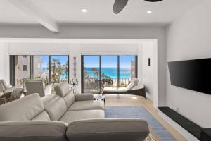 a living room with a couch and a flat screen tv at Elegant Beachfront Penthouse | Casa Del Mar Delfin in San José del Cabo