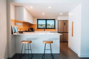 a kitchen with a white counter and two stools at Daybreak Loft. Willunga in Willunga