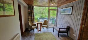 a living room with chairs and a table and a window at Hawthorn in Glencoe