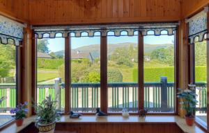 a large window in a house with a view of the mountains at Holly Tree Cottage in Glencoe +18 photos