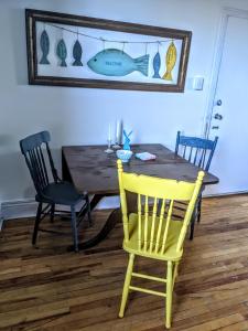 a dining room table with a yellow chair and a mirror at Downtown Apt 2 executive 21 Queens Road in St. John's