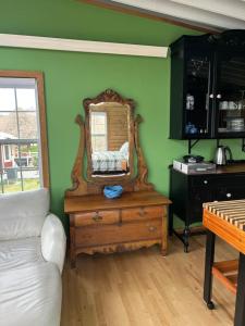 a green room with a mirror on a wooden dresser at Cupids Guest House and SheShed in Brigus