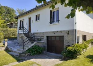 a white house with a garage and stairs at Gîte 6 pers jardin clos proche plage et lac Cantal in Lacapelle-Viescamp