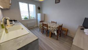 a kitchen with a table and chairs and a refrigerator at Gîte 6 pers jardin clos proche plage et lac Cantal in Lacapelle-Viescamp +20 photos