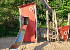 a small red play house with a slide at Gîte 6 pers jardin clos proche plage et lac Cantal in Lacapelle-Viescamp