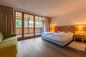 a bedroom with two beds and a large window at Alpin Natur Hotel Brückele in Braies
