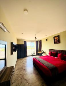 a bedroom with a red bed and a large window at Everfreshhighviewcottage in Ooty