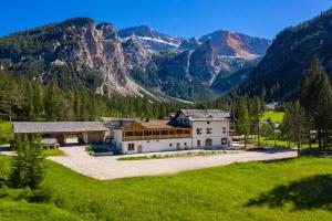 a house in a field with mountains in the background at Alpin Natur Hotel Brückele in Braies