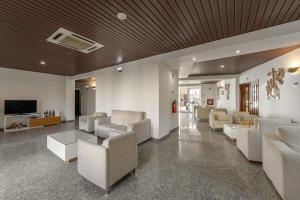 ein Wohnzimmer mit weißen Sofas und einem Fernseher in der Unterkunft Hotel Comendador in Bombarral