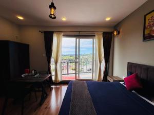 a bedroom with a bed and a view of a balcony at Everfreshhighviewcottage in Ooty