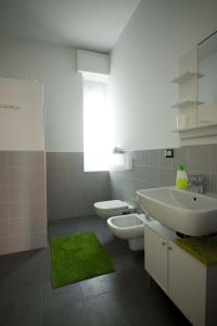 uma casa de banho com 2 WC, um lavatório e um espelho. em Green Bed Bergamo Guest House & Residence em Bérgamo