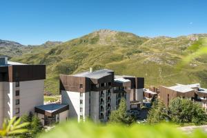 a building with a mountain in the background at Résidence Pierre & Vacances Les Combes in Les Menuires