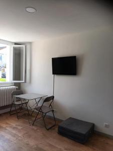 a room with a table and a tv on a wall at Comfortable studio dans une maison au calme in Bellerive-sur-Allier
