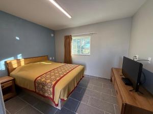 a bedroom with a bed and a flat screen tv at Bel-Air Motel in Alice