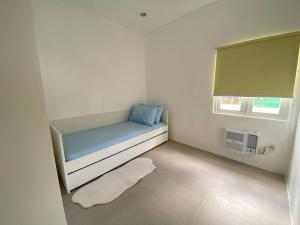 a small room with a blue bed and a window at Cozy Haven Batulao in Calo