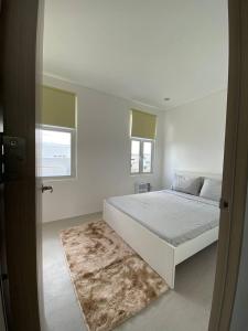 a white bedroom with a bed and a rug at Cozy Haven Batulao in Calo