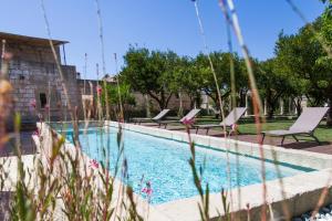 a swimming pool with lounge chairs next to a building at Antica Dimora Giardini Segreti in Giuggianello