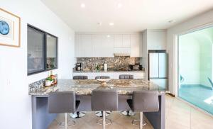 a kitchen with a counter with chairs around it at Mar y Sol 16th floor Condo in Rosarito