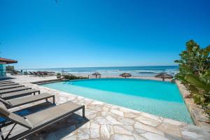 a swimming pool with chairs and the beach at Mar y Sol 16th floor Condo in Rosarito