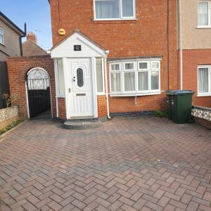 a house with a white door on a brick driveway at Spacious 2 bedoom house in Wyken
