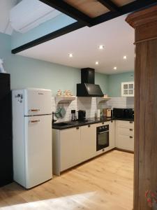 a kitchen with a white refrigerator and a stove at Le Loft du Renard, gîte cosy au coeur de la nature boisée à Namur Wépion, une parenthèse douce dans la vallée mosane in Namur