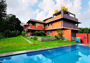 a house with a swimming pool in front of it at Pepper Corn Retreat By Travent Mug in Sakleshpur
