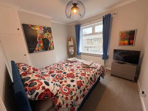 a bedroom with a bed with a flowered comforter and a television at Bright Harrogate flat 2 beds great location in Harrogate