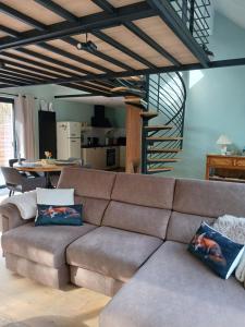 a brown couch in a living room with a staircase at Le Loft du Renard, gîte cosy au coeur de la nature boisée à Namur Wépion, une parenthèse douce dans la vallée mosane in Namur